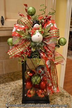 a christmas decoration on top of a counter in a kitchen with green and red ornaments