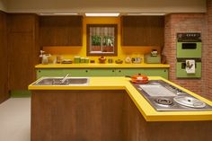 a kitchen with yellow counter tops and green appliances on the counters, along with brick walls