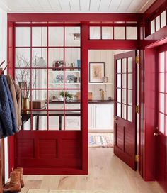 an open door leading into a kitchen with red trim and wood flooring on the walls