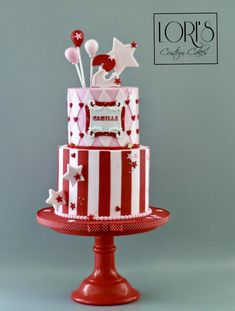 a red and white striped cake with stars on the top is sitting on a pedestal