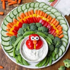 a turkey made out of veggies and carrots on a plate with dip in the middle