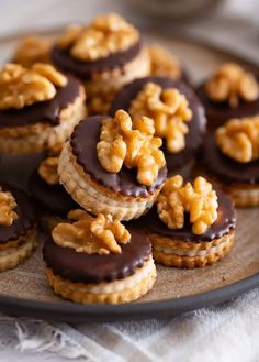 there are many cookies on the plate with walnuts and chocolate icing around them