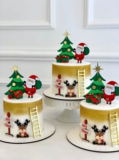 three cakes decorated with christmas decorations and santa clause on the top one has a ladder