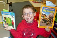 a young boy holding up two books in front of him