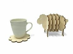 a cup and saucer are next to a sheep shaped coaster with the shape of a mug on it