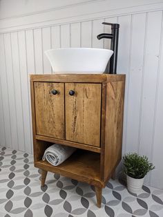 a wooden cabinet with a white bowl on top and a black faucet next to it