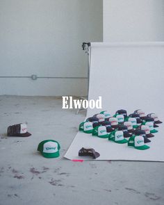 several hats lay on the ground in front of a white backdrop with words that read elwood