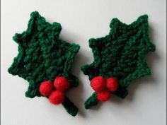 two crocheted holly leaves with red berries on them, one is green and the other is red