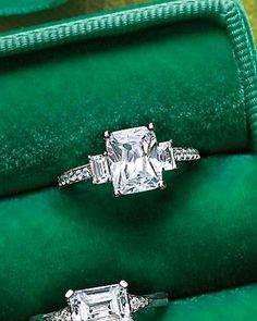 two engagement rings sitting on top of a green velvet ring box with the words emerald cut diamond engagement ring