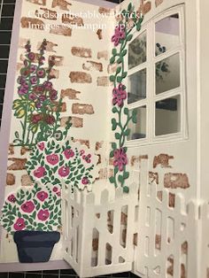 an open book with flowers and plants on the cover, sitting next to a window