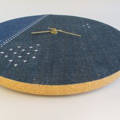 a clock made out of blue jeans with white stars on the bottom and gold hands