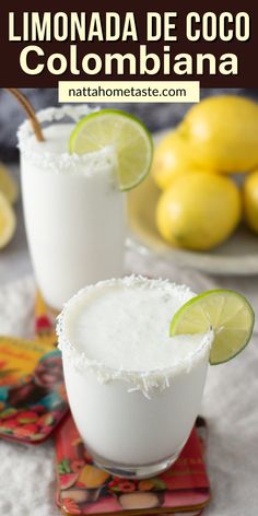 two glasses filled with lemonade and coconut on top of a table next to limes