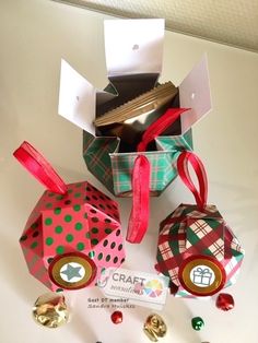 three small gift boxes with ribbons and tags on them sitting on a white surface next to some candy