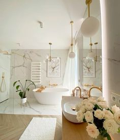 a bathroom with marble walls and flooring has white flowers in vases on the counter