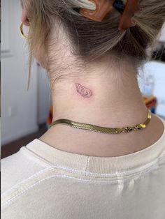 a woman's neck with a small tattoo on the back of her left side