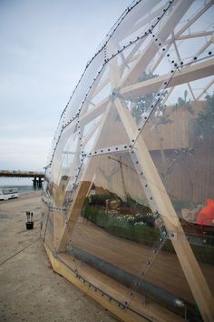 a large glass structure sitting on top of a dirt field