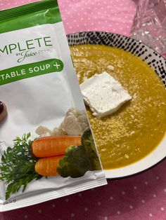 a bag of soup sitting on top of a table next to a bowl of vegetables