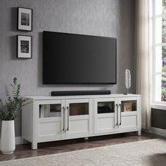 a large flat screen tv mounted on top of a white entertainment center in a living room