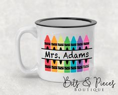 a white coffee mug with colorful crayons on it and the words mrs adams's bits & pieces boutique