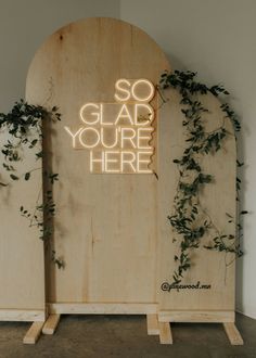 a wooden sign that says so glad you're here with vines growing on it