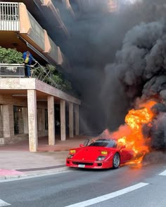 a red sports car on fire in front of a building