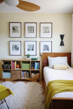 a bed room with a neatly made bed and several pictures on the wall above it