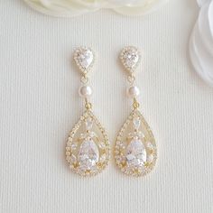 Delicate and elegant, the Esther gold wedding earrings are lovely drop earrings made with sparkling cubic zirconia in golden tones and accented with pearls. I have created the bridal gold drop earrings with large cubic zirconia teardrops. The wedding earrings are dangled from 6mm pearls and put onto cubic zirconia detailed halo set ear posts. All material is 14k gold plated brass with stainless steel posts. Also available in silver/rhodium plated brass and rose gold plated brass finishes. Please Gold Pearl Wedding Earrings, Gold Dangle Earrings Wedding, Expensive Earrings, Gold Wedding Earrings, Rose Gold Bridal Earrings, Bridal Earrings Drop, Wedding Earrings Drop