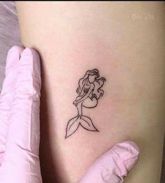 a little mermaid tattoo on the side of a woman's thigh, with her arm behind her back