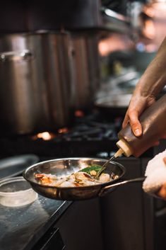 a person cooking food in a pan on the stove