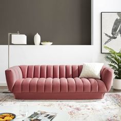 a living room with a pink couch and coffee table in front of a gray wall