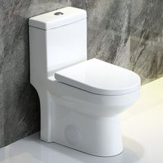 a white toilet sitting on top of a bathroom floor next to a gray stone wall