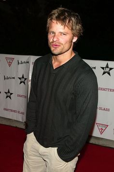 a man standing on a red carpet in front of a white and black wall with stars