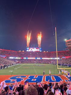 fireworks light up the night sky over a football stadium full of fans and players during a game