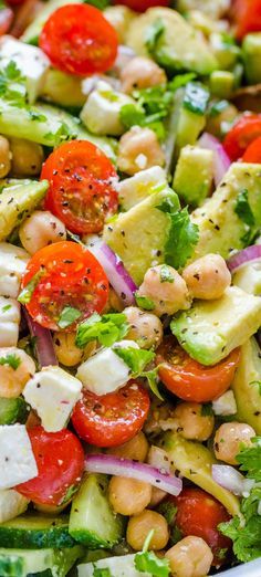 a salad with chickpea, tomatoes and cucumber in it is shown