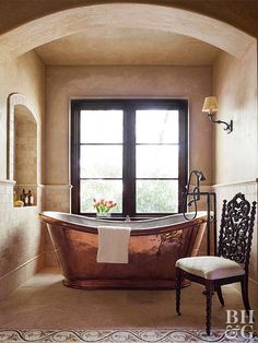 an old fashioned bathtub in the middle of a bathroom with a chair next to it