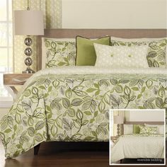 a green and white bed in a bedroom next to a night stand with a lamp on it