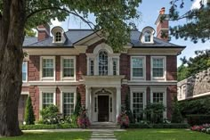 a large brick house surrounded by lush green grass and trees in front of the house