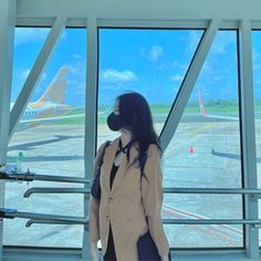 a woman wearing a face mask standing in front of an airport window