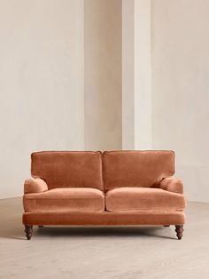 an orange couch sitting on top of a hard wood floor next to a white wall