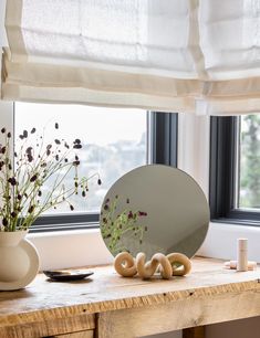 a vase with flowers and candles on a table next to a mirror that says love