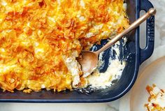 a casserole dish is shown with a wooden spoon in it and some other food on the side