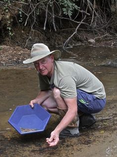 a man kneeling down in the water holding a blue bowl