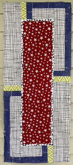 a red, white and blue quilt hanging on a wall