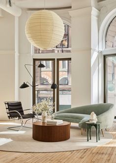 a living room filled with lots of furniture next to large windows and wooden flooring