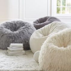 three bean bag chairs sitting on top of a white rug in front of a window