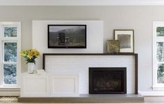 a living room filled with furniture and a fire place in front of two large windows