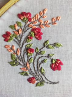 a close up of a embroidery on a piece of cloth with red and green flowers