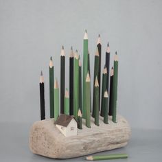 there are many pencils arranged in the shape of a house on top of a piece of wood