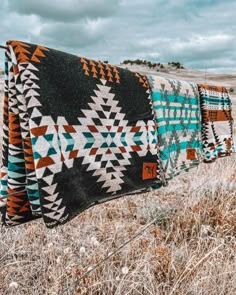 three blankets hanging on a fence in the middle of nowhere