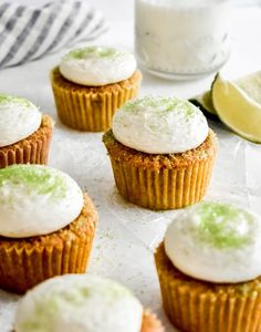 small cupcakes with white frosting and lime zest are on a baking sheet